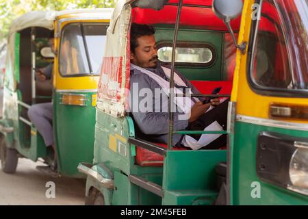 Auto rickshaw drivers using mobile phone while sitting inside Stock Photo