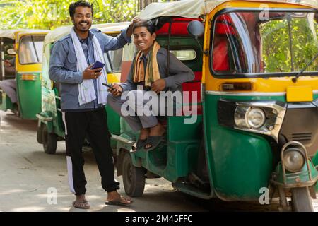 Auto rickshaw drivers using their mobile phones at auto stand Stock Photo