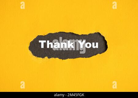 Torn yellow paper with Thank you text on black background. Stock Photo