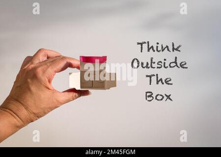 Word, Think outside the box next to fingers holding an open small box. Stock Photo