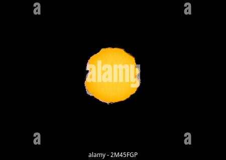 Torn black hole on yellow paper background. As template for text or advertisement. Stock Photo