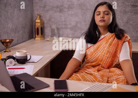 Woman meditating at her desk in office Stock Photo