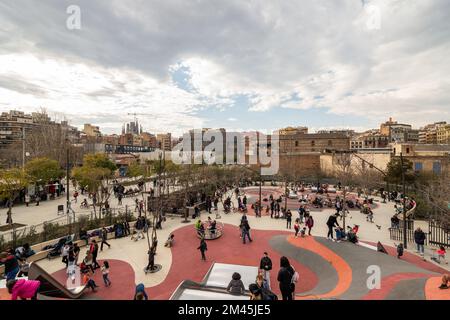 03 MARCH 2022, BARCELONA, SPAIN: Children with parents playing in playground in the center of the city on cloudy day Stock Photo