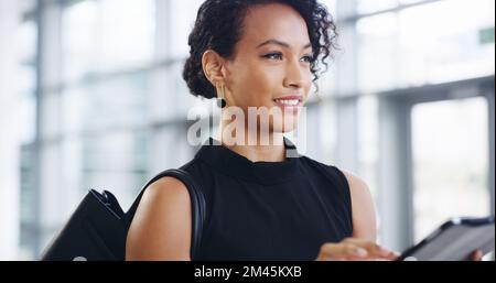 Business never sleeps. a young businesswoman using a digital tablet while walking through a modern office. Stock Photo