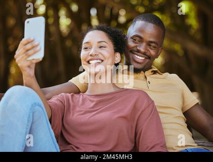 Black couple, phone and selfie with smile at outdoor nature park for travel, happiness and social media profile picture content update. Happy man and Stock Photo
