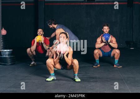 Group of people doing squats with weights during a training class Stock Photo