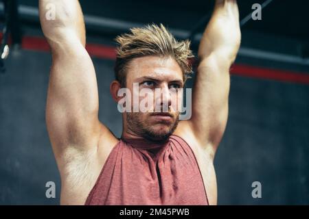 Close up portrait of a concentrated man doing pull ups in a gym Stock Photo