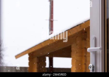 Snow blurred background. Snowflakes in focus outside the window. The concept of weather, snowfall. village life. An open door to the courtyard. Empty Stock Photo
