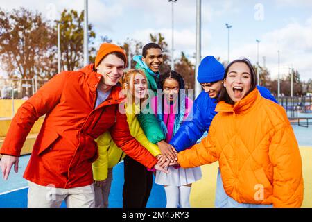 Multiracial group of young happy friends meeting outdoors in winter, wearing winter jackets and having fun - Multiethnic millennials bonding in a urba Stock Photo