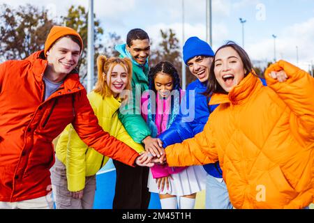 Multiracial group of young happy friends meeting outdoors in winter, wearing winter jackets and having fun - Multiethnic millennials bonding in a urba Stock Photo