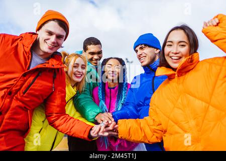 Multiracial group of young happy friends meeting outdoors in winter, wearing winter jackets and having fun - Multiethnic millennials bonding in a urba Stock Photo