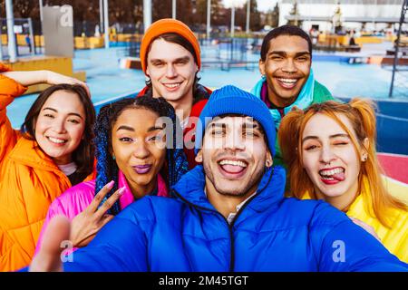 Multiracial group of young happy friends meeting outdoors in winter, wearing winter jackets and having fun - Multiethnic millennials bonding in a urba Stock Photo