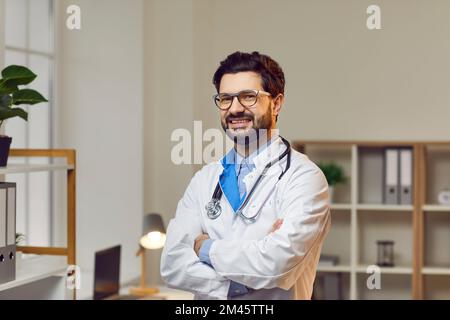Confident smiling doctor posing with arms crossed in hospital Stock Photo
