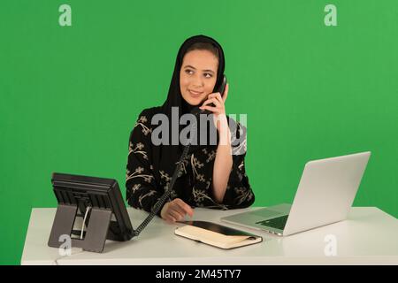 Arab woman talking on telephone in office. Stock Photo