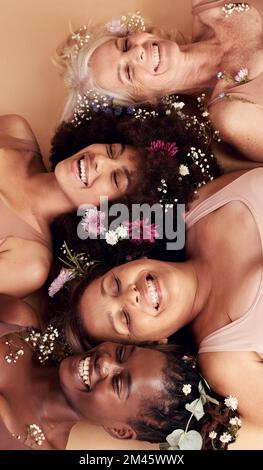 Top view, women diversity or faces with flowers on studio background in empowerment, divine feminine energy or self love. Smile, happy or skincare Stock Photo