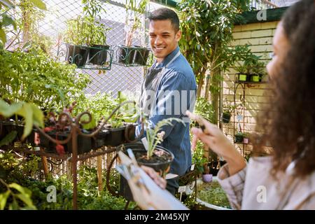 Gardening, flowers and plants with a couple checking in the garden together for a botany hobby at home. Nature, spring and sustainability with a man Stock Photo