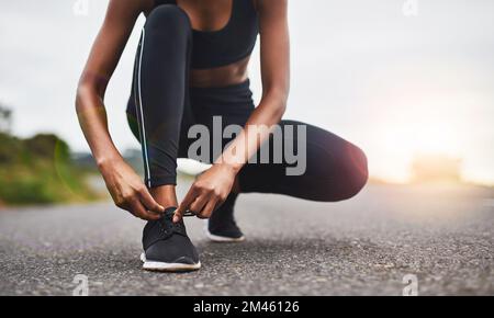 Fasten them up well. Closeup shot of a sporty woman tying her shoelaces while exercising outdoors. Stock Photo