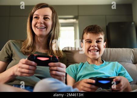 Son and mother playing video game at home, Family spending time together, Happy relationship, Online entertainment and leisure activity Stock Photo