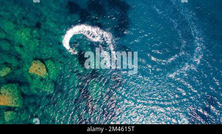 Aerial top view of a motor powerboat forming a circle of waves Stock ...