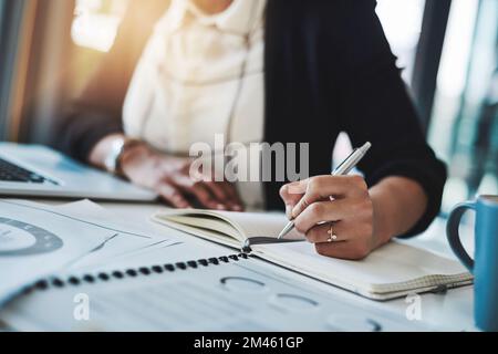 Jot it down and just do it. a businesswoman making notes at her desk in a modern office. Stock Photo