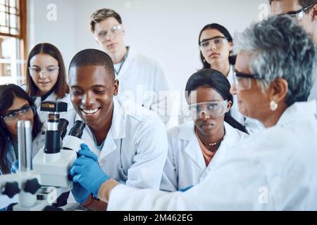 Education, science and teacher with students using microscope for chemistry, biology and medical research . Medicine, healthcare lab and mentor with Stock Photo