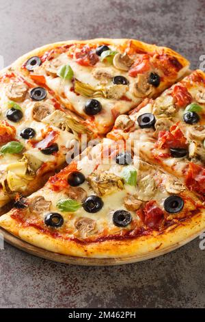 Pizza capricciosa with white mushrooms, ham, artichoke, tomatoes, olives, parmesan and mozzarella on wooden board on the table. Vertical Stock Photo