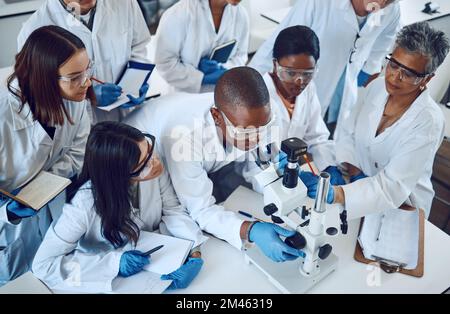 Student, microscope and science in university class, group and learning with woman lecturer, education or study. Students, scientist and medical Stock Photo