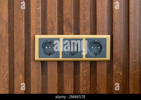 Modern triple socket mounted on wood veneer wall Stock Photo