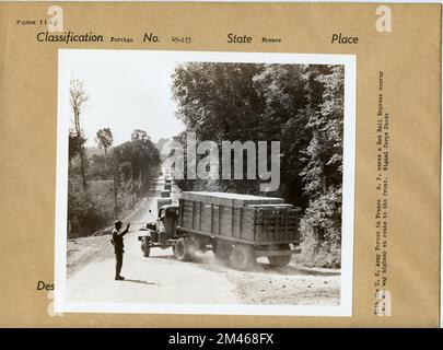 M.P. Waves a Red Ball Express Convoy on a One Way Highway En Route to the Front. Original caption: With the U.S. Army Forces in France: M.P. waves a Red Ball Express convoy on a one way highway en route to the front. Signal Corps Photo. State: France. Stock Photo