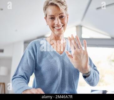 Senior woman, hand and waving on video call, house zoom conference or social networking communication in house or Canada home. Portrait, smile and Stock Photo