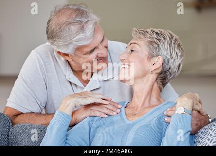Love, senior couple and relax on a sofa, smile and happy while sharing intimate moment, bond and romance in living room. Happy family, retirement and Stock Photo