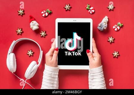 Bangkok, Thailand. December 2022 Smartphone Tik Tok application icon, logo on screen, wireless headphones on red background Trendy social media networ Stock Photo