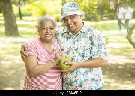 Happy indian senior couple having coconut water at summer park. Old ...