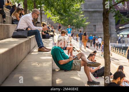 People sit on the steps of a riverside public space on the Chicago Riverwalk. Stock Photo