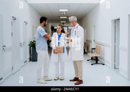 Team of doctors discussing something at hospital corridor. Stock Photo
