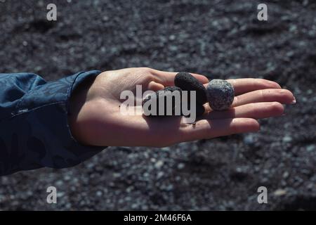 Close up woman showing black pebbles on palm concept photo Stock Photo