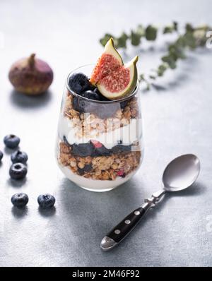 Yogurt with baked granola and berries in white ceramic plate on wooden ...