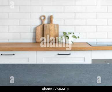 Wooden blue countertop with free space for mounting a product or layout against the background of a blurred white kitchen with cutting board and plant Stock Photo