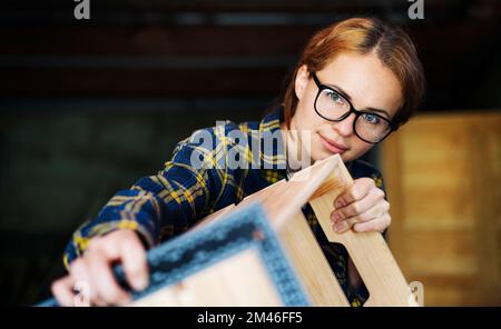 Young woman wearing glasses measuring wooden object using angle rulet. Stock Photo