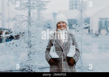 Portrait of happy senior woman in winter at outdoor ice skating rink. Stock Photo