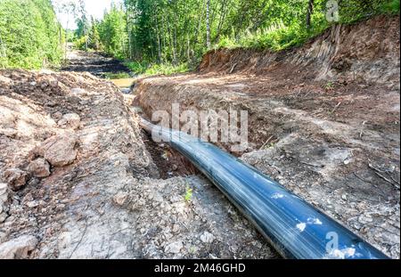 Laying a plastic gas pipeline pipe in a trench in the summer. Gas pipeline is installed under the ground Stock Photo