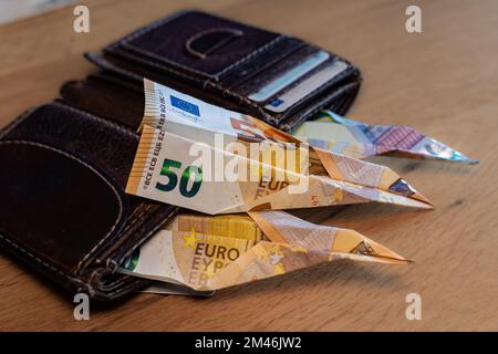 Banknotes looking out of a wallet. Are folded into a paper airplane Stock Photo