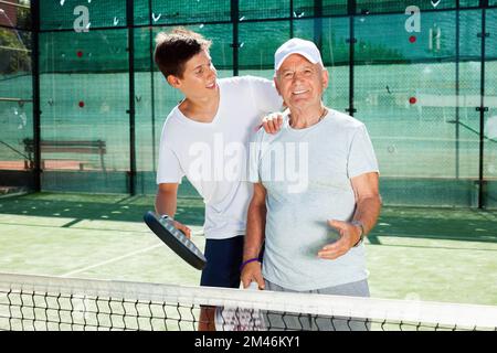 older man and a young man talking on court playing paddle Stock Photo