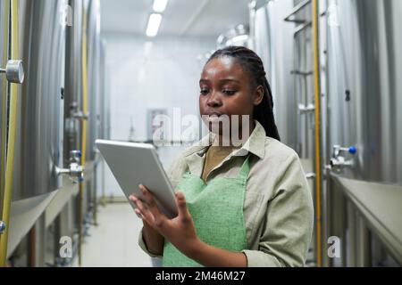 Brewery worker managing fermentation process via application on tablt computer Stock Photo