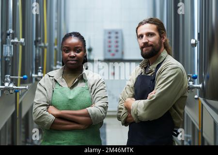 Smiling team of microbrewery workers standing with arms crossed Stock Photo