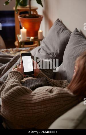 Woman lying in bed and using phone Stock Photo