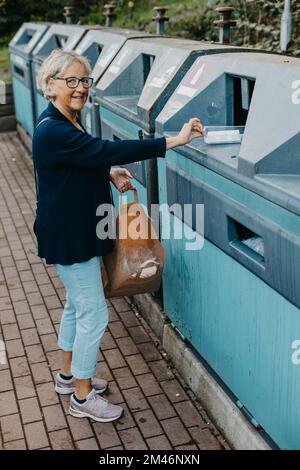 Woman putting plastic in recycling bin Stock Photo