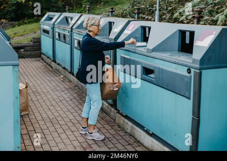 Woman putting rubbish in recycling bin Stock Photo