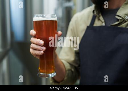 Worker holding big glass of beer produced in microbrewery Stock Photo