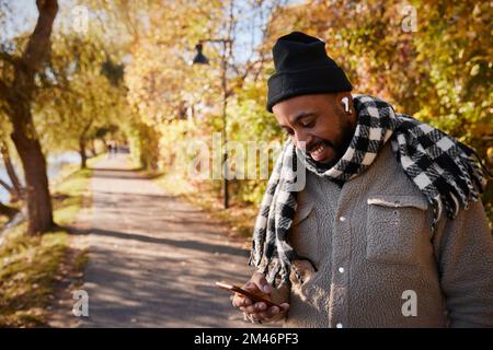 Man using phone in autumn park Stock Photo